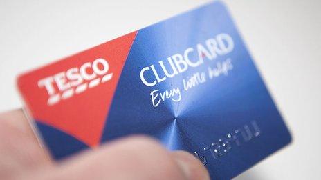 A person holds a blue-and-red Tesco Clubcard in their hand in close-up