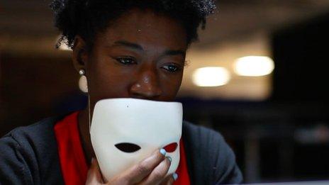 Joy Buolamwini holding a white mask