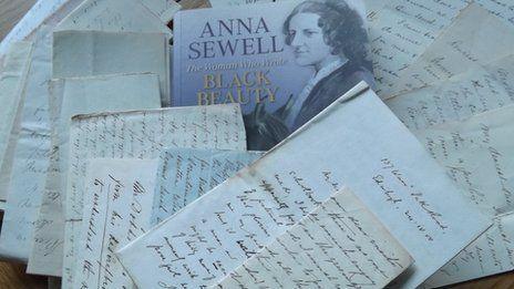 A pile of handwritten letters.  A book about Anna Sewell is in the centre of the collection.