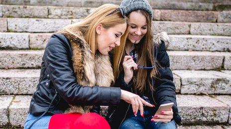 young women pointing at phone