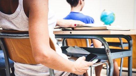 student holding phone in class