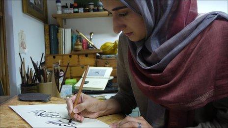 Soraya Syed, an Islamic calligrapher, draws a symbol in ink.