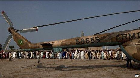 Pakistanis crowd around a helicopter after it delivered aid in Sindh Province, southern Pakistan, 20 August 2010