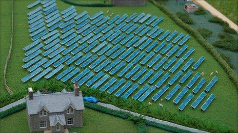 Model of a farm house with solar panels in adjacent field
