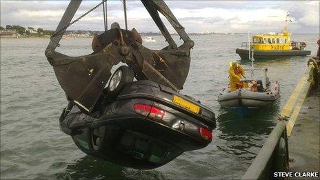 A crane lifting the car from the sea