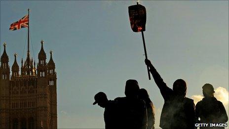 Protesters burn placards at an anti-tuition fees demonstration in London's Parliament Square