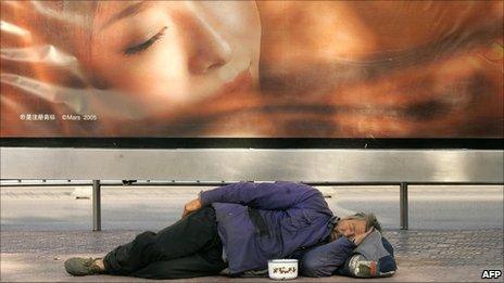 File image of a homeless man sleeping underneath an advertising board in Beijing