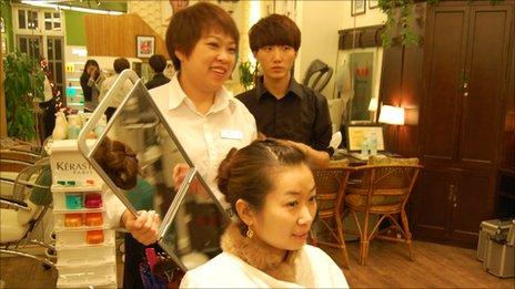 Cai Huilin holds up a mirror to a customer's head in Beijing