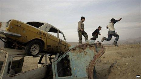 Afghan boys jump down from old vehicles in Kabul in January 2010