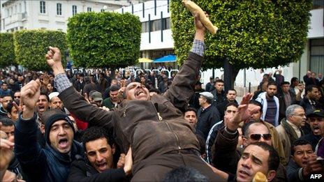 A Tunisian man holding a baguette is carried by fellow protesters during a demonstration in Tunis on 18 January 2011