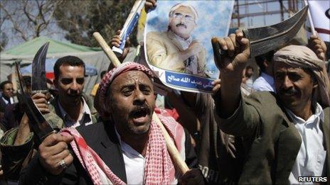 Government loyalists armed with daggers brandish a poster of Yemeni President Ali Abdullah Saleh in the capital Sanaa, 14 February