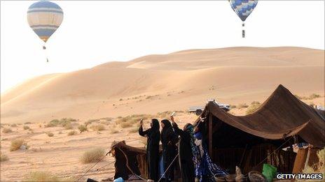 Tuareg women of nomadic tribes take pictures with their mobile phones of hot air balloons flying over the desert of Ghadames, western Libya, September 2009