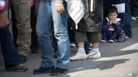 Japanese residents queue up to receive aid supplies in the devastated city of Sendai