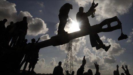 Rebels celebrate on Gaddafi tank destroyed by air strike, between Benghazi and Ajdabiya (20 March 2011)