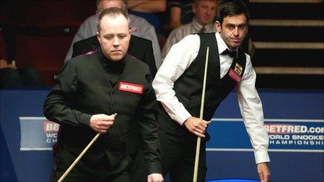 Ronnie O'Sullivan looks on as John Higgins sizes up a pot in their quarter-final