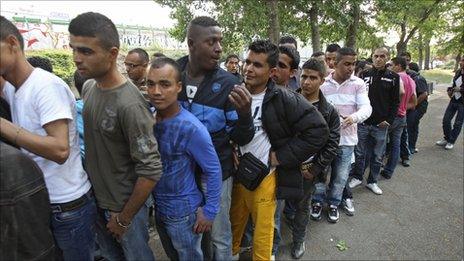 Tunisian migrants line up for food in a Paris square, 26 April