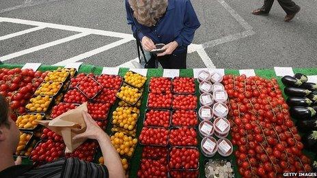 A woman buys tomatoes at a farmers' market in Wimbledon