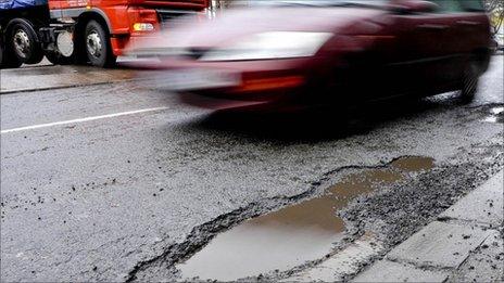 Car drives past pothole