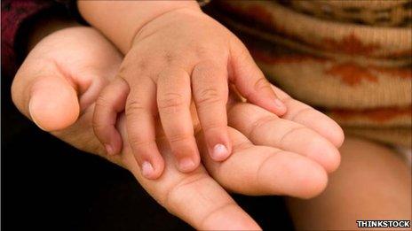 A baby's hand rests on a woman's hand