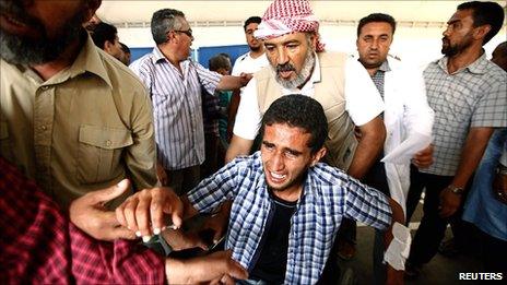 An injured Libyan rebel fighter mourns his fallen comrade killed by a Grad rocket belonging to government forces at the hospital in Misrata, 8 June 2011