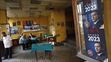 Men sit in a tea house in Istanbul with Prime Minister Tayyip Erdogan's election campaign posters on the window, 9 June