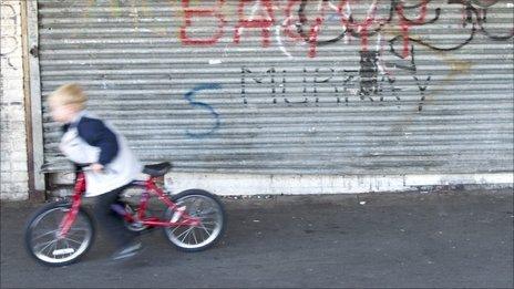 A child rides past a closed shop on a bicycle