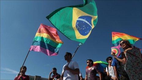 People wave Gay movement flags, left and right, and a Brazilian one, centre, during a march against homophobia in Brasilia, Brazil, Wednesday, 18 May 2011