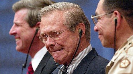 Donald Rumsfeld grimaces while listening to a translation