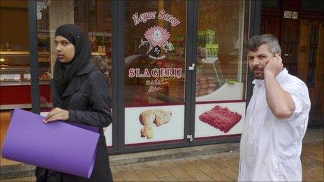A butcher talks on his mobile phone outside a halal butchers in Amsterdam (31 March 2011)