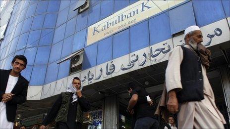 Afghans walk past a branch of Kabul Bank (file photo)