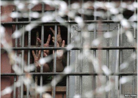 Detainees make victory salutes from behind the bars of a detention centre in Minsk, 6 July