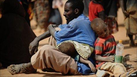 Somali man who fled violence and drought in Somalia with his family sits on the ground outside a food distribution point in the Dadaab refugee camp in northeastern Kenya on 5 July 2011