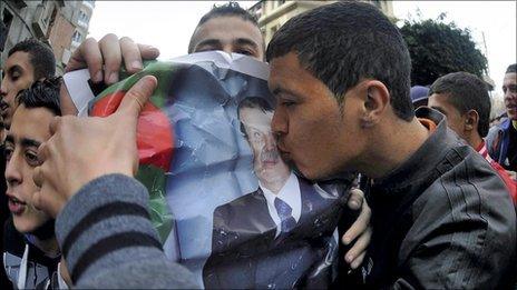 A man kissing a poster of Algeria's leader