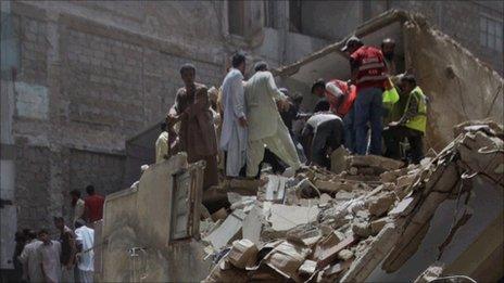 Rescuers look through the rubble of the building which collapsed in Karachi on 4 August 2011