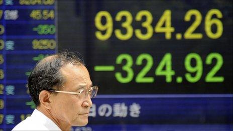 Man in front of Nikkei share board