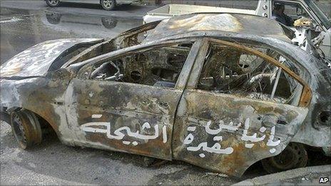 Arabic graffiti on a burnt-out car reads: "Baniyas is the grave of the shabiha."