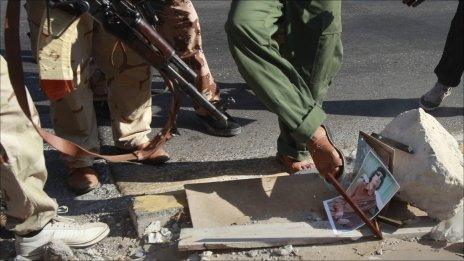 Rebel fighters in Tripoli destroy a picture of Col Gaddafi