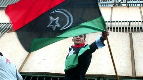 A man waving the rebel Libyan flag at the Harare embassy (24 August 2011)