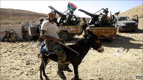 A Libyan fighter loyal to the National Transitional Council (NTC) rides a donkey at an outpost in Wadi Dinar in the area along the frontline with the town of Bani Walid on September 11, 2011.