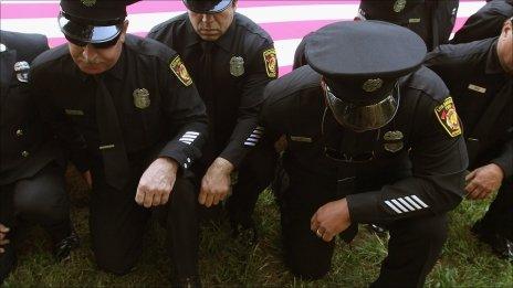 New York City Firefighters kneel in front of the US flag and mark a moment of silence on the 10th anniversary of 9/11
