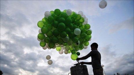 Boy releases green balloons into the sky