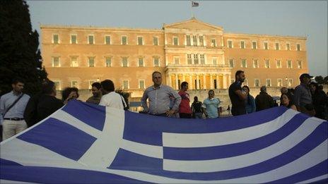 Protesters hold a Greek flag during a rally