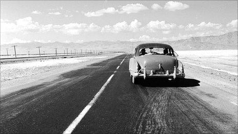 single car on desert highway in 1950's