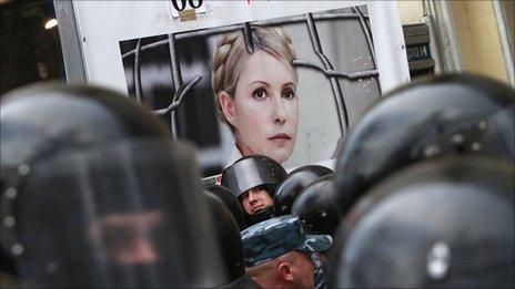 Riot police stand guard near a board displaying a portrait of former Ukraine PM Yulia Tymoshenko at a rally in Kiev