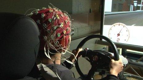 A researcher's brain signals are monitored as he use a driving simulator.