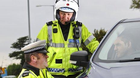 Traffic police officers speak to a driver