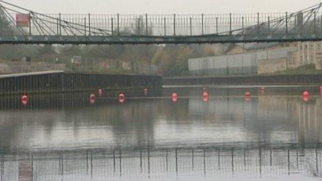 Bright orange buoys stop river traffic from sailing underneath the Victoria Bridge on the River Avon in Bath