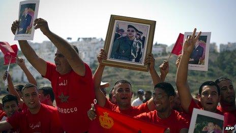 Moroccans hold up portraits of King Mohammed VI along a road in Tangiers 29 September 29, 2011.