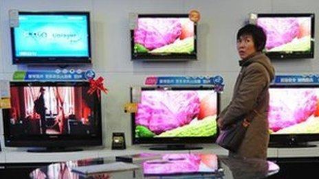 A woman walking past television sets on display at an electronics and home appliances store in Zhengzhou in central China's Henan Province (file photo)