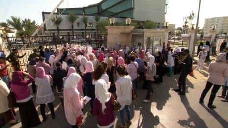 Women, many with their mouths' taped, attend a protest outside the interim prime minister's office in Tripoli